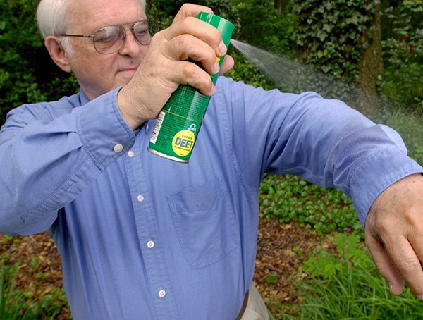 Applying repellent to clothing.